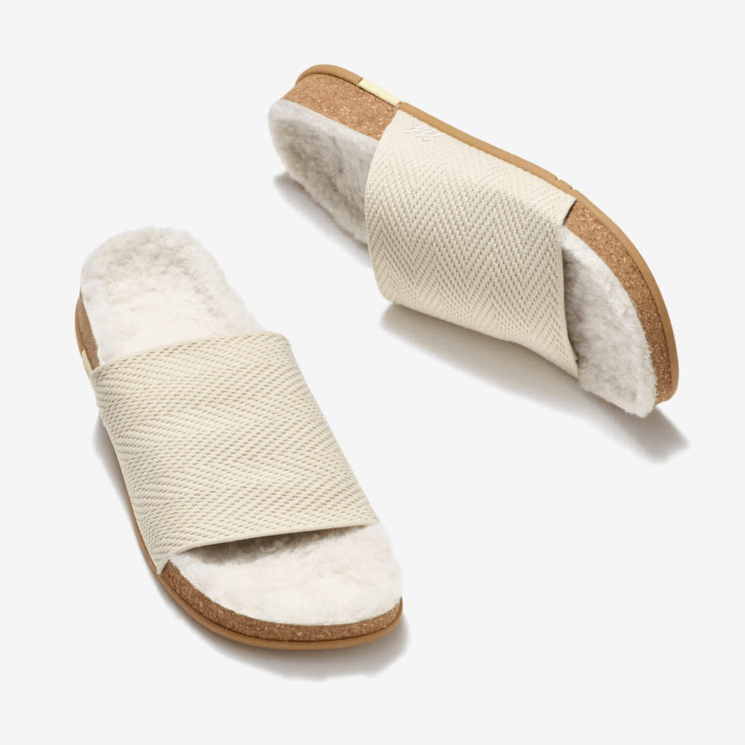 A pair of MESSAGE Creme Brulee Cozy Shaw Slides with vegan shearling lining and cork footbeds.