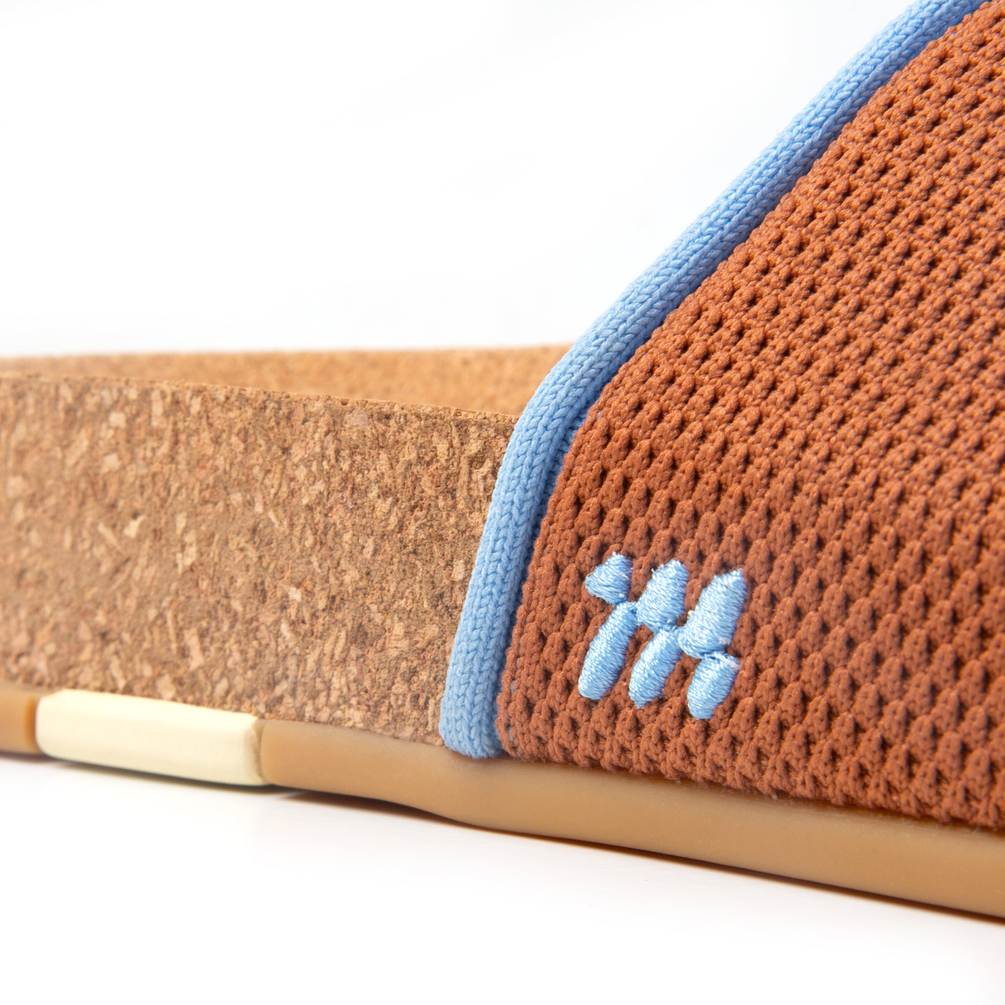 Close-up of a sandal with brown mesh and blue trim on a white background