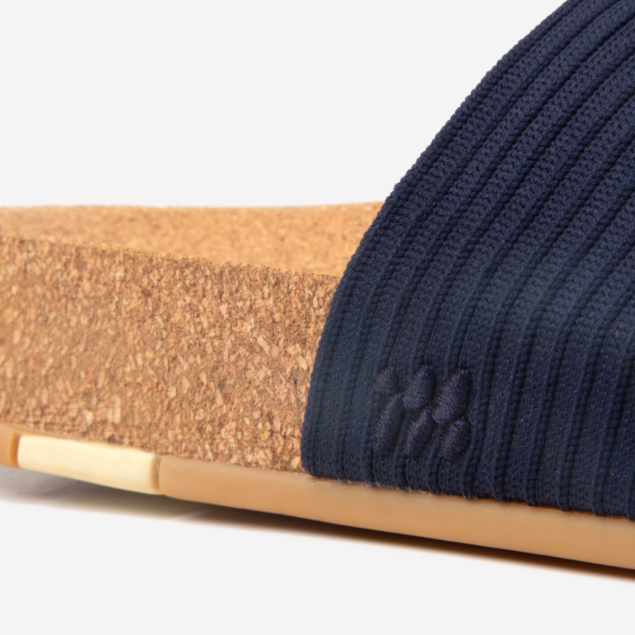 Navy blue knit beanie on a wooden stick with a white background