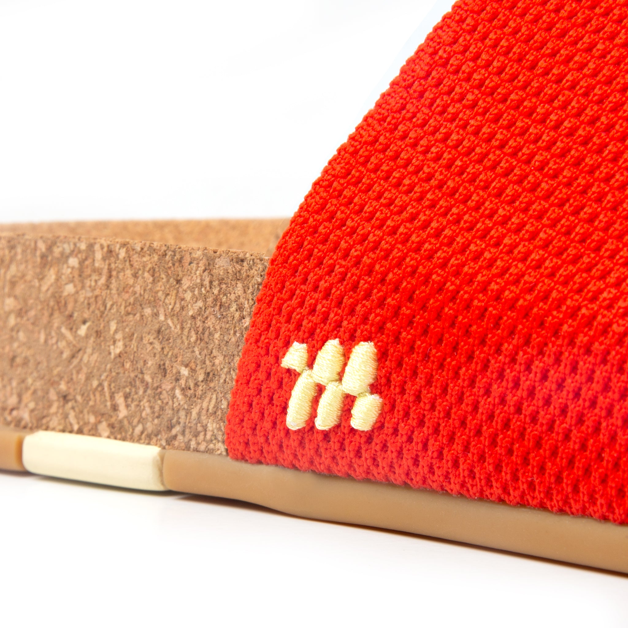 Close-up of a red woven sandal with a beige sole on a white background