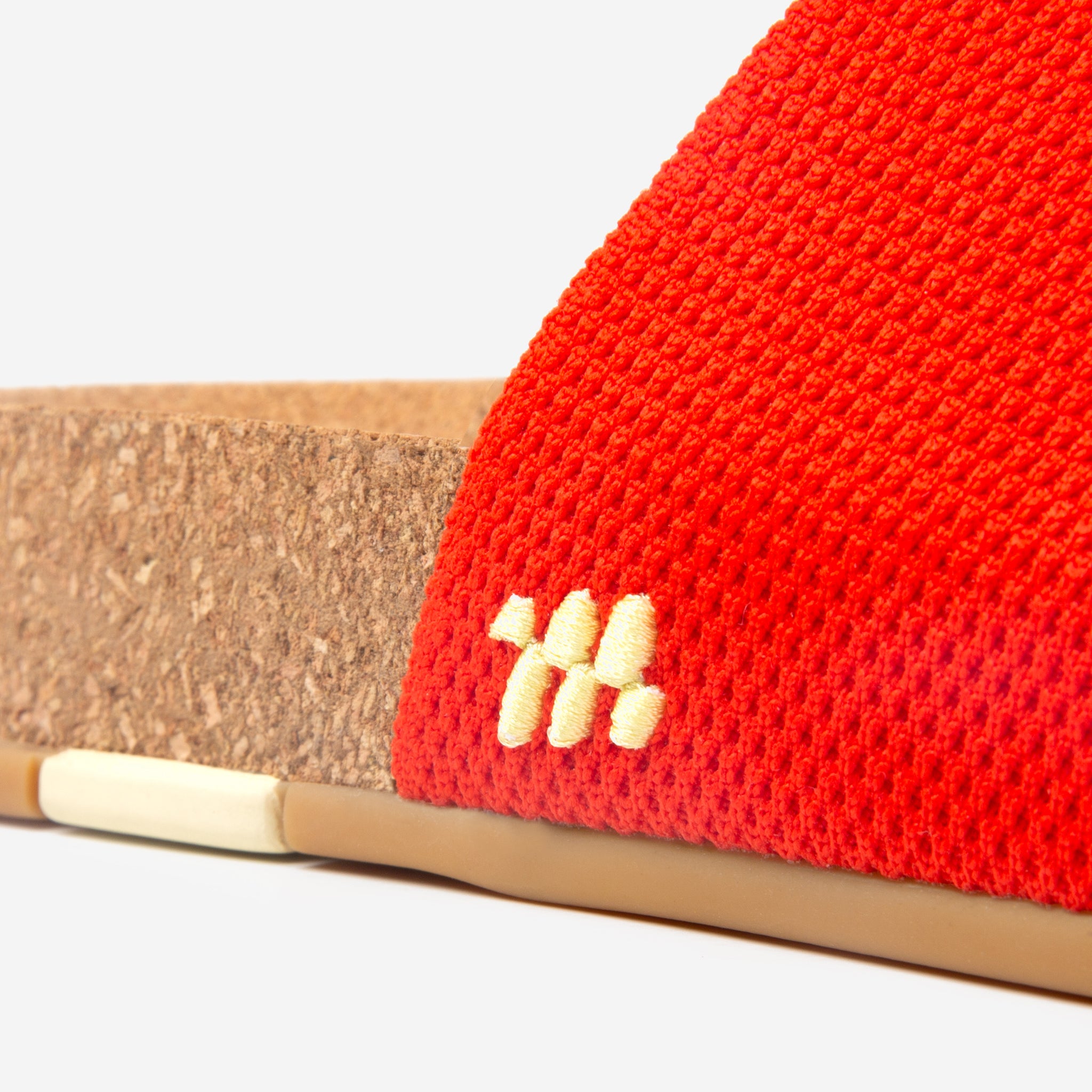 Close-up of a red woven sandal with a beige sole on a white background