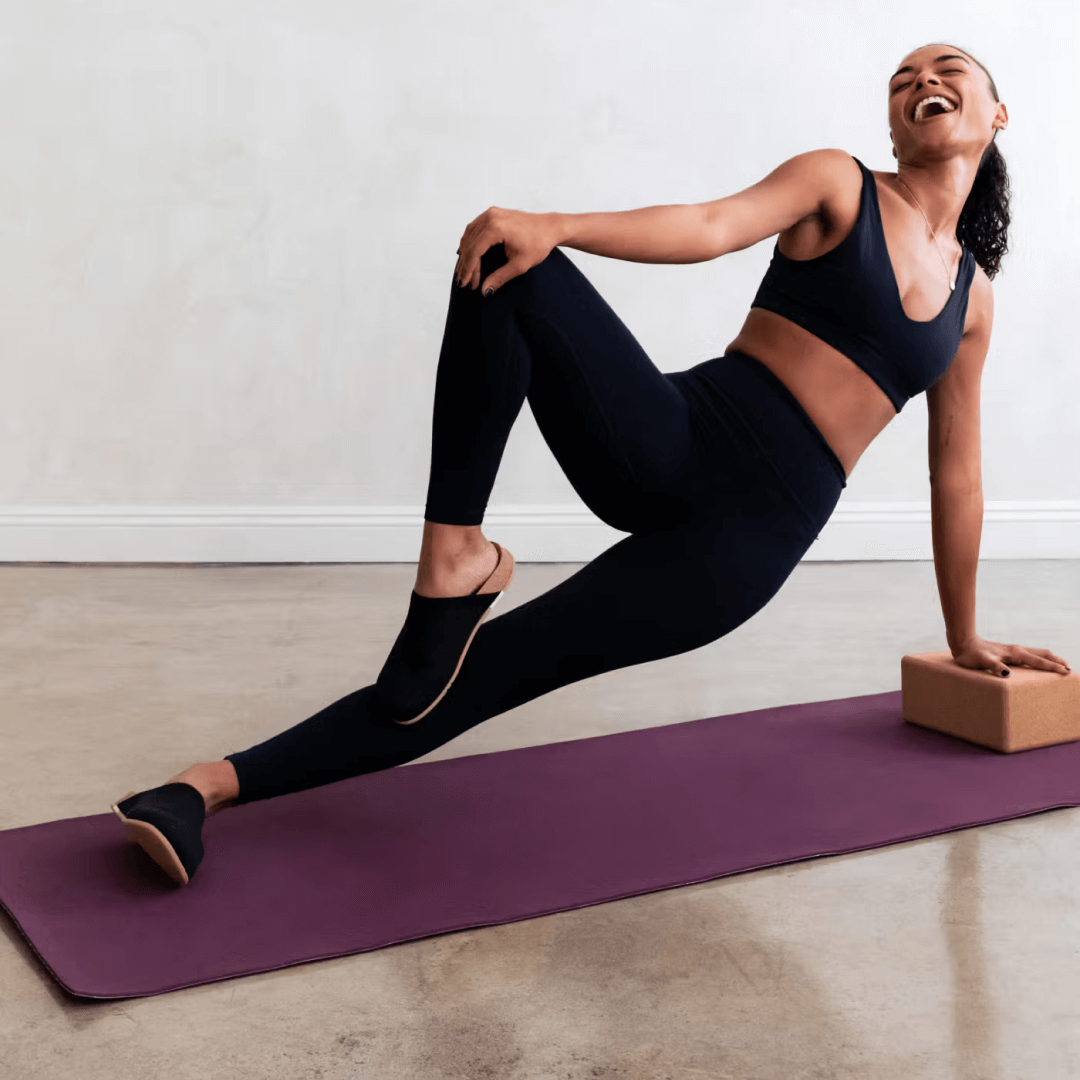 Woman doing yoga while wearing black Henning Classic Mules.