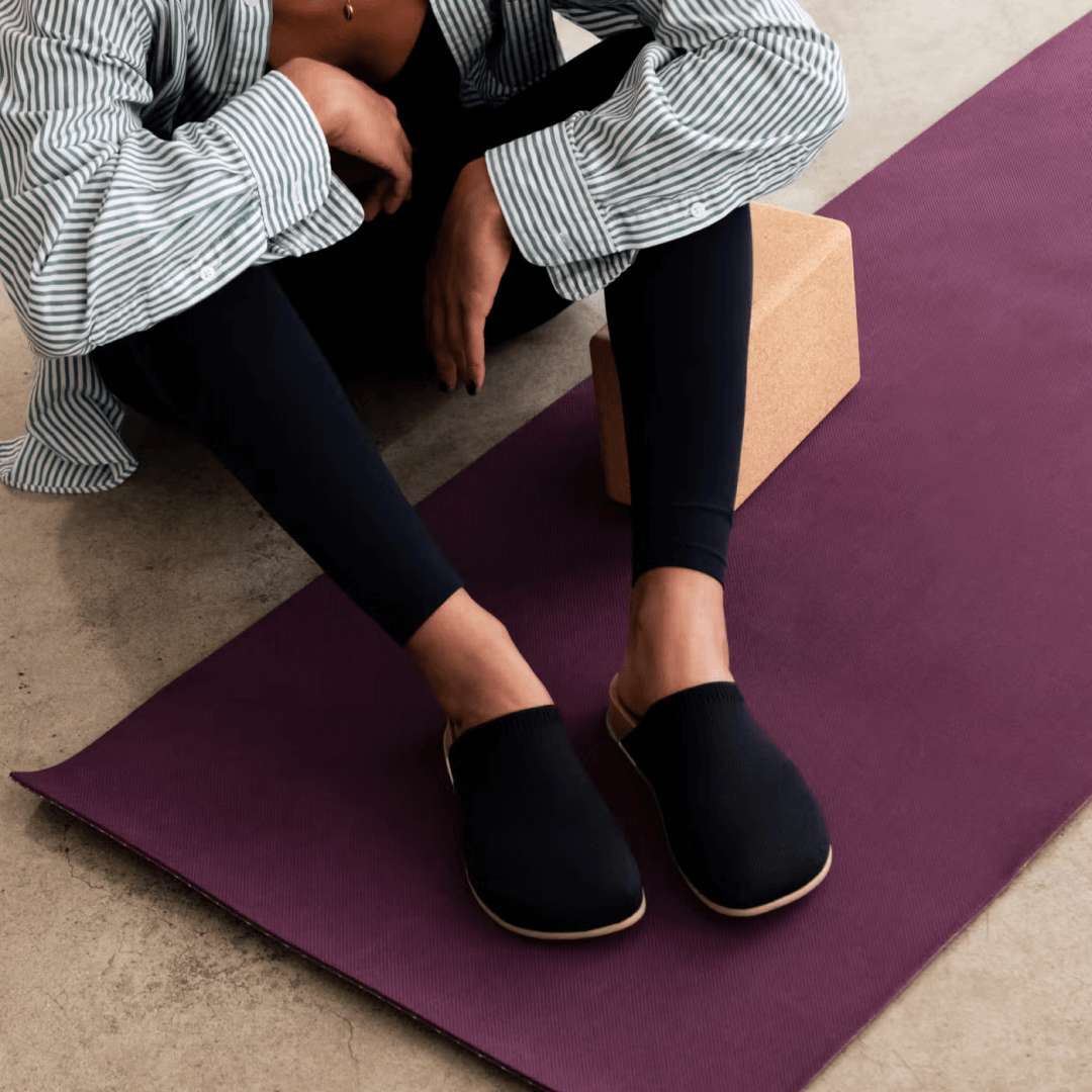 Woman sitting on yoga mat wearing Henning Classic Mule black.
