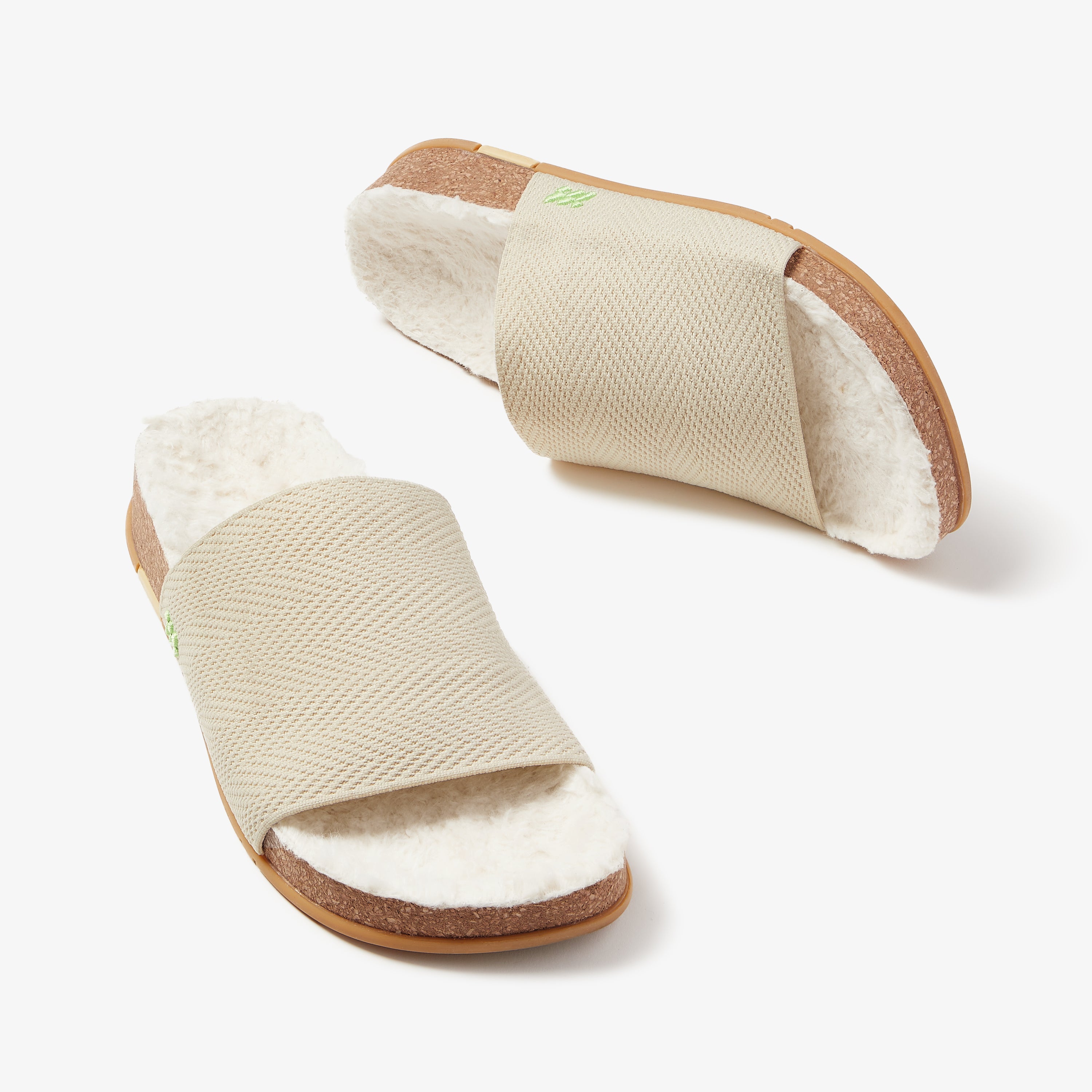 Pair of beige slippers with brown soles on a white background