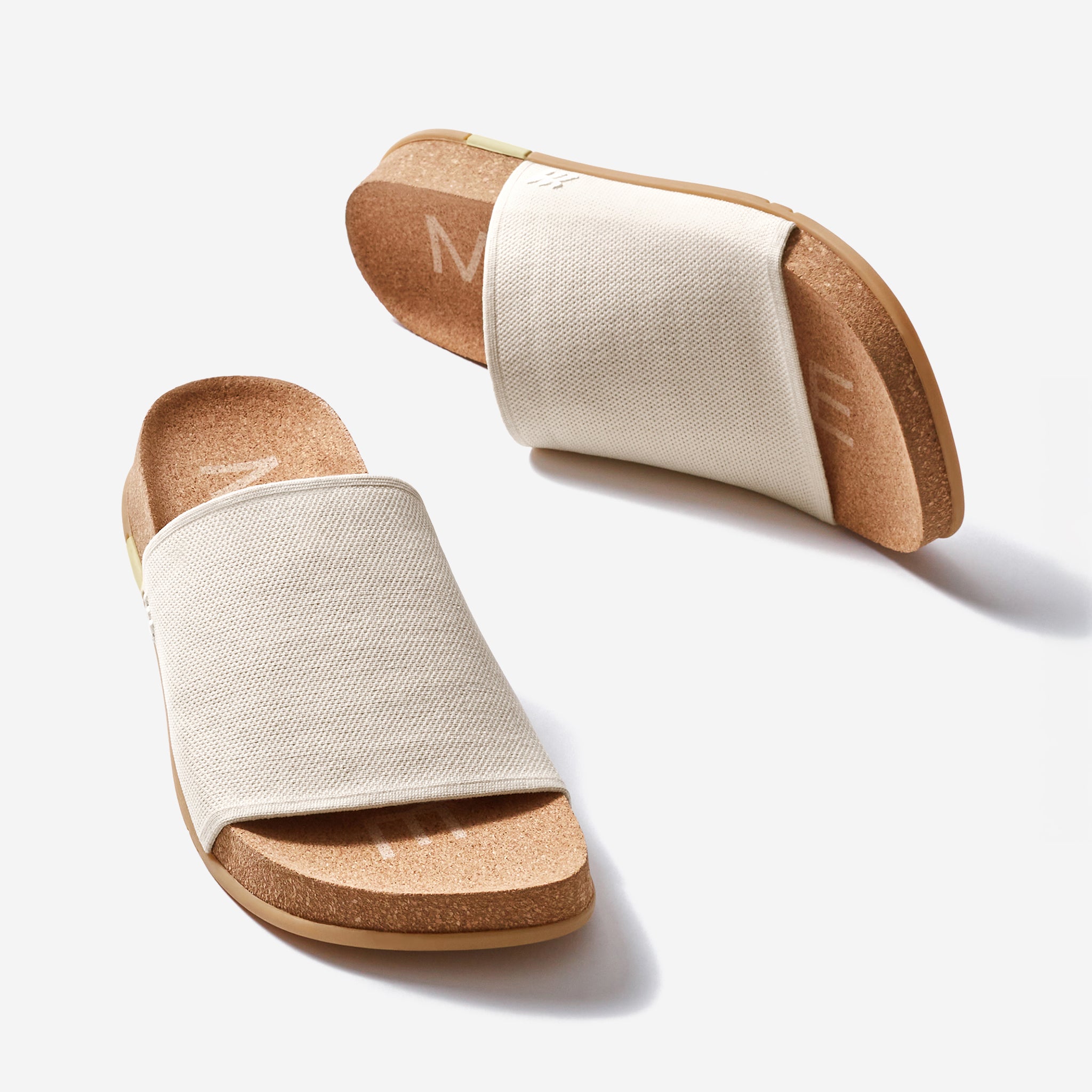 Pair of sandals with beige canvas straps and brown cork soles on a white background