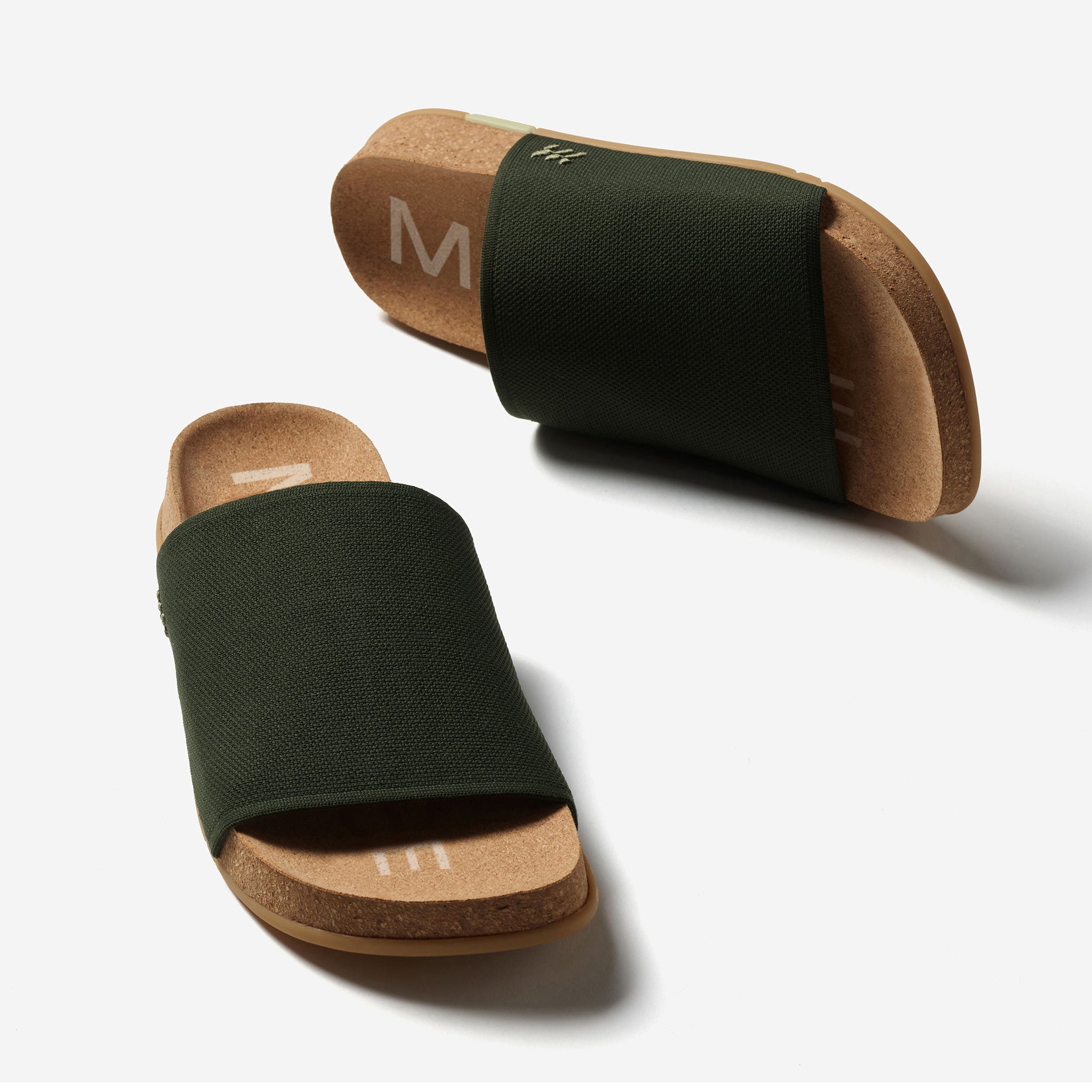 Pair of black slides with cork soles on a white background